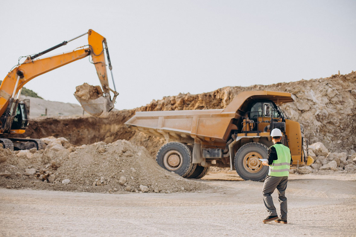 Male construction worker with bulldozer in sand quarry